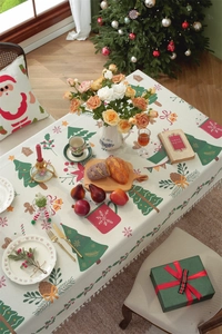 Close-up of festive Christmas tablecloth with fringe, featuring Santa and tree patterns