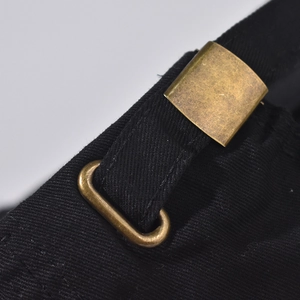 Close-up of vintage bronze metal buckle and distressed black cotton on baseball cap