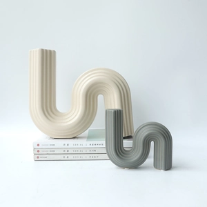 Modern S-shaped ceramic vases with vertical ribbing in beige and sage green colors