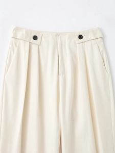 Vue détaillée du pantalon beige à taille haute avec boutons noirs doubles à la ceinture