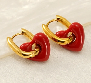 Macro shot of gold U-shaped earrings featuring glossy 3D red heart pendants