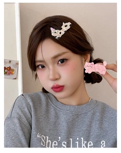Detail showing acetate cat hair clips in cow pattern and pink wave on a model