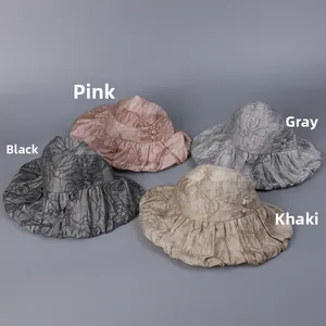 Flat lay of foldable sun hats in pink, grey, black, and khaki with pleated texture