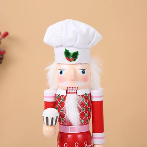 Detailed view of chef nutcracker with white fabric hat and a striped cupcake accessory