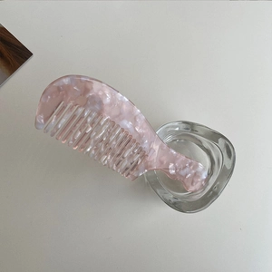 Pink marble texture acetate hair comb in a clear glass jar on white table