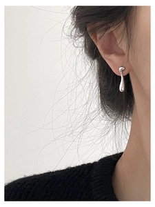 Close-up of asymmetrical fluid silver teardrop earring on model showing modern minimalist style