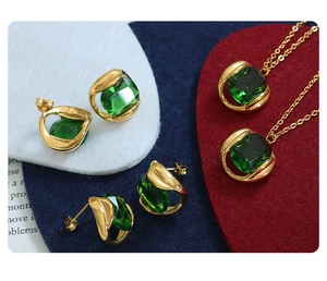 Macro shot of gold necklace and earrings set with square emerald green crystals