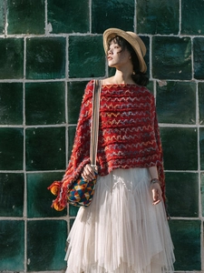 Gros plan sur le poncho en tricot rouge à motifs de vagues et glands décoratifs sur modèle