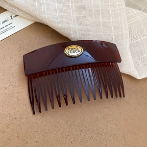Detailed macro view of vintage tortoiseshell hair comb with oval golden metal plaque
