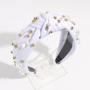 Detailed view of white knotted headband with heart pearls, gold beads and rhinestones