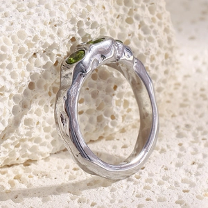 Macro view of silver lava texture ring featuring three olive green gemstones on coral stone