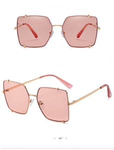 Dettaglio occhiali da sole oversize in metallo dorato con lenti rosa chiaro e perline