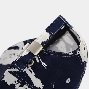 Detail of adjustable metal buckle and graffiti print on a cotton canvas baseball cap
