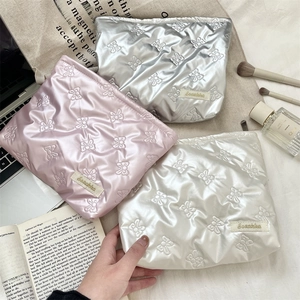 Detailed shot of quilted PU makeup bags in silver, pink, and white with bow patterns