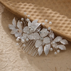Close-up of bridal hair comb with silver leaves, white pearls, and sparkling crystals