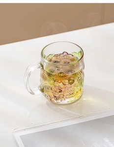 Detailed close-up of hand-painted grape relief on a transparent glass coffee mug