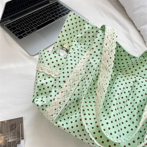 Detail of mint green polka dot tote bag with white lace trim and handy side pocket