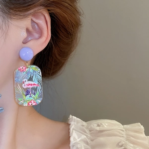 Close-up of artistic flamingo earrings featuring purple studs and acrylic pendants