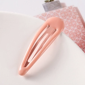 Detailed macro view of a 5cm pink candy-colored drop snap hair clip on a textured stand