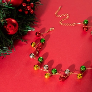 Chunky Christmas necklace with red, green, and gold beads on a festive red background