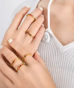 Detail of five stackable gold plated rings with colorful zircon stones on a female hand