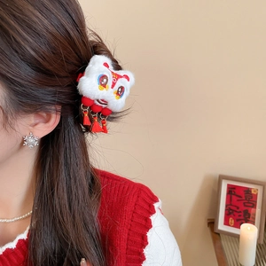 Détail d'une pince à cheveux lion en peluche avec glands rouges sur un chignon