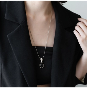 Detail of silver snake chain with oval black resin pendant worn with a black blazer