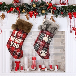 Plaid pet Christmas stockings with faux fur trim hanging on a festive decorated fireplace