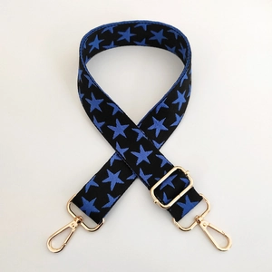 Detail of adjustable wide star pattern bag strap with durable gold metal lobster clasps
