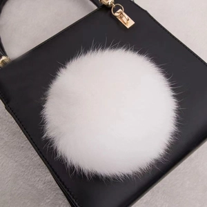 Vue détaillée d'un pompon en fourrure de renard blanche sur fond en cuir noir
