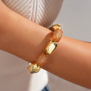 Detail of bohemian gold and amber resin irregular chunky beaded bracelet on a wrist