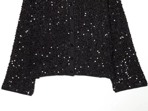 Detail shot of black sequin cardigan showing fine texture and button closure