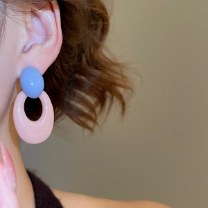 Macro view of blue and pink acrylic oval hollow drop earrings worn by a model