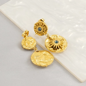 Macro view of gold-tone starburst earrings with blue stone on white ceramic plate