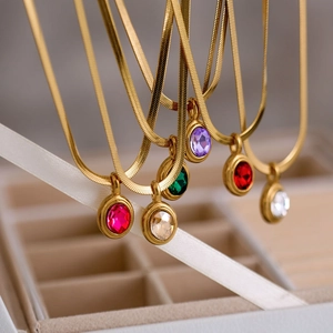 Golden flat snake chain necklaces with colorful oval zircon pendants on white ribbon