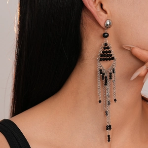 Détail de boucles d'oreilles pampilles argentées avec perles noires au design triangle