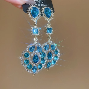 Close-up of sparkling blue teardrop fringe earrings with silver-tone rhinestone inlay
