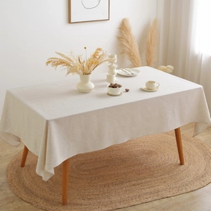 Detailed texture of beige linen rectangular tablecloth on wooden table in a cozy room