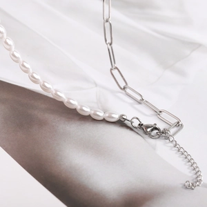 Detailed close-up of pearl stitching and silver chain link on stainless steel necklace
