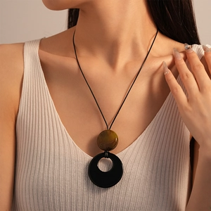 Detail of vintage resin circle pendant with marble texture on long black cord necklace