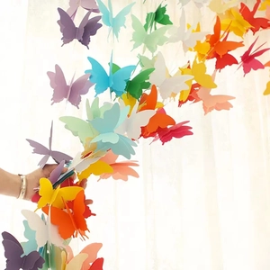 Hand holding 3D rainbow butterfly paper garland for birthday party room decoration