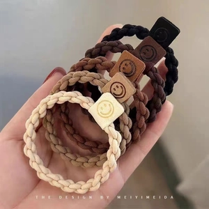 Detail of high-elastic braided hair ties in five colors with leather smile pendants