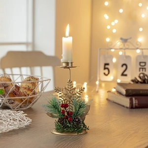Golden snowflake iron candle holder with pine cones and red berries on wooden desk