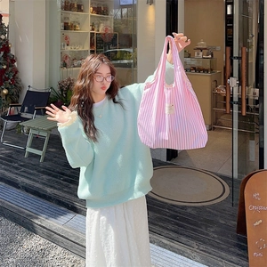 Detail of pink and white striped canvas tote bag with large capacity held by a model