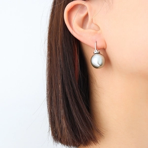 Élégantes boucles d'oreilles en titane plaqué or 18K avec perle grise sur un mannequin