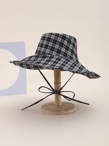 Detail of checkered sun hat with a matching ribbon bow on a wooden display stand