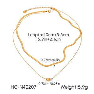 Detailed view of golden double-layer necklace with snake chain and heart pendant