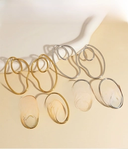 Dettaglio di orecchini di tendenza in acciaio inox oro e argento con curve a spirale
