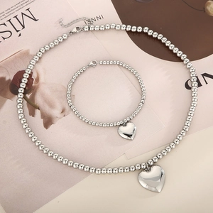 Detailed view of silver beaded necklace and bracelet set with 3D heart charms on a magazine