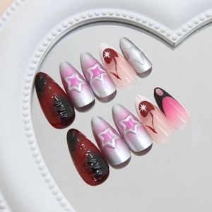 Unghie finte stiletto metalliche con motivi a stella e sfumature rosa su vassoio